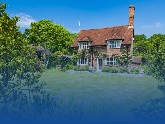 A countryside house with a well kept garden in the sun