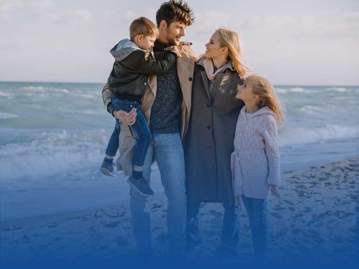 A father on a beach holding his wife and children, thinking he needs a will.